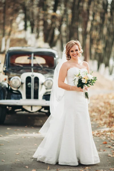 Красива щаслива наречена з букетом біля ретро-автомобіля восени — стокове фото
