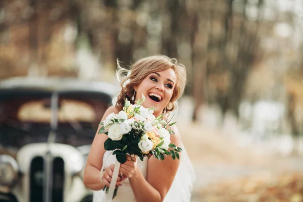 Мбаппе счастливая невеста с букетом у ретро-автомобиля осенью — стоковое фото