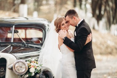 Şık düğün çift, Gelin, damat öpüşme ve retro arabanın yakınında sonbaharda sarılma