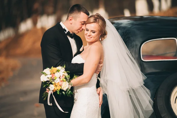 Élégant couple de mariage, mariée, marié baisers et câlins près de voiture rétro en automne — Photo