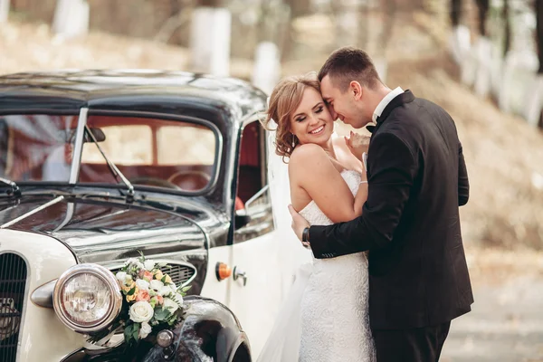 Elegante coppia di nozze, sposa, sposo baciare e abbracciare vicino auto retrò in autunno — Foto Stock