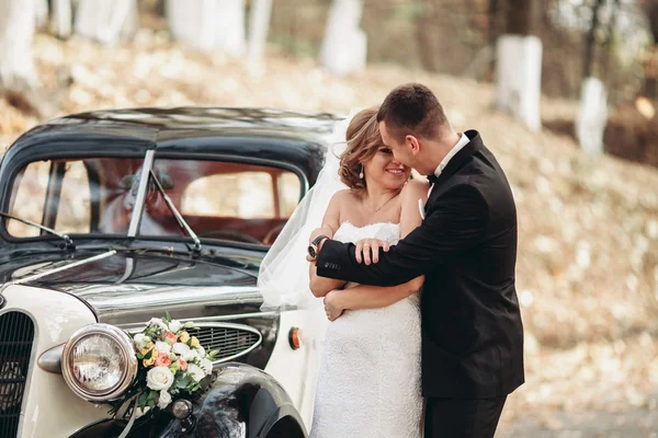 Elegante coppia di nozze, sposa, sposo baciare e abbracciare vicino auto retrò in autunno — Foto Stock