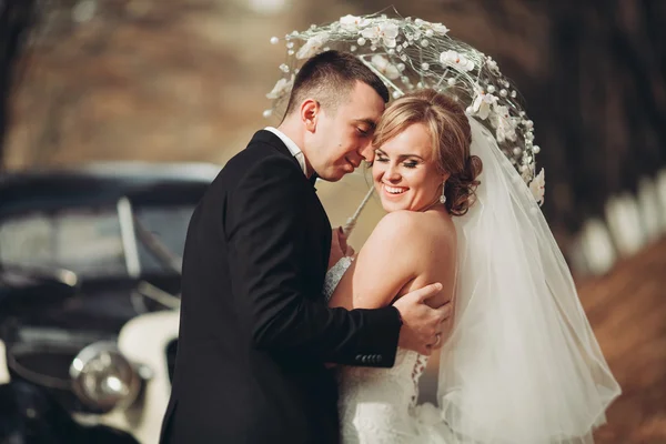 Стильная свадебная пара, невеста, жених целуется и обнимается около ретро-машины осенью — стоковое фото