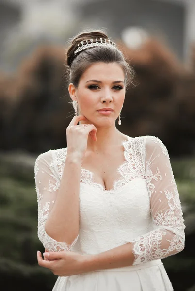 Gyönyörű menyasszony és egy luxus fehér ruhában pózol az óvárosban — Stock Fotó