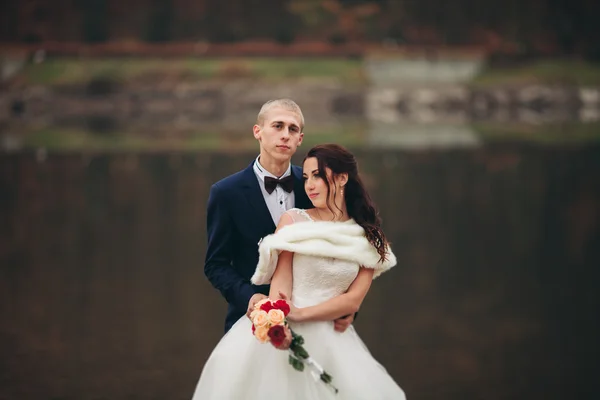 El amor y la pasión - el beso de la pareja casada joven de boda cerca del lago — Foto de Stock