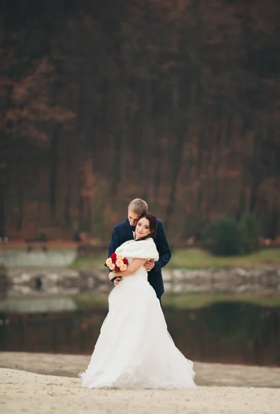 Kärlek och passion - kyss av gift unga brudparet nära lake — Stockfoto
