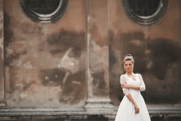 Maravillosa novia con un lujoso vestido blanco posando en el casco antiguo — Foto de Stock