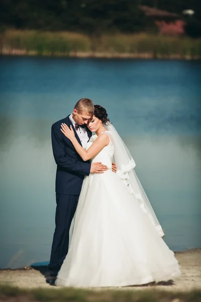 Love and passion - kiss of married young wedding couple near lake — Stock Photo, Image