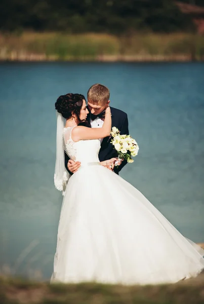 El amor y la pasión - el beso de la pareja casada joven de boda cerca del lago —  Fotos de Stock