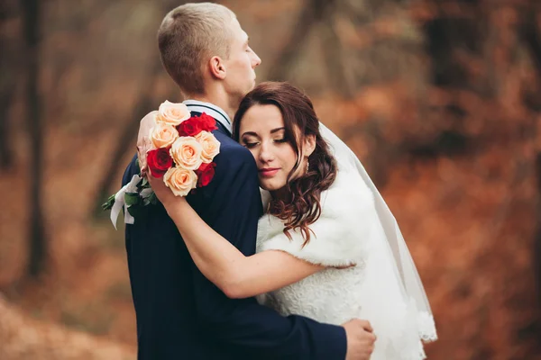 Happy bröllopsparet, bruden och brudgummen poserar i park hösten — Stockfoto