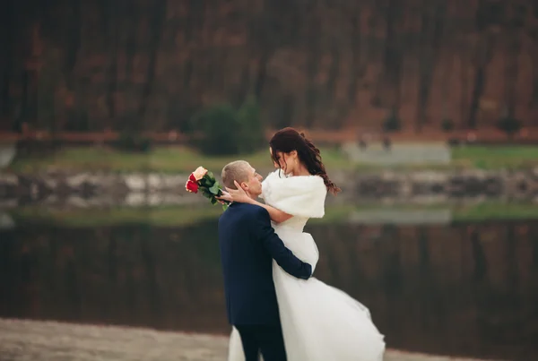 El amor y la pasión - el beso de la pareja casada joven de boda cerca del lago —  Fotos de Stock