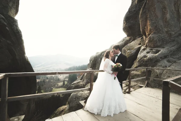 Boda pareja enamorada besándose y abrazándose cerca de rocas en hermoso paisaje —  Fotos de Stock