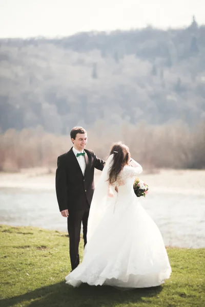 Hermosa pareja de boda, novia, novio posando y caminando en el campo sobre el fondo de las altas montañas —  Fotos de Stock
