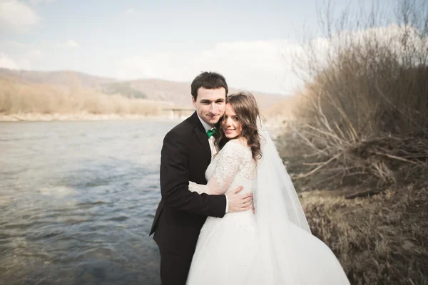 Felice sposi, sposi in posa sul fiume con una splendida vista — Foto Stock