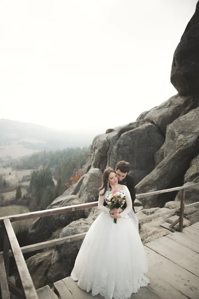 Pareja feliz boda, novia y novio posando cerca de rocas con hermosas vistas — Foto de Stock