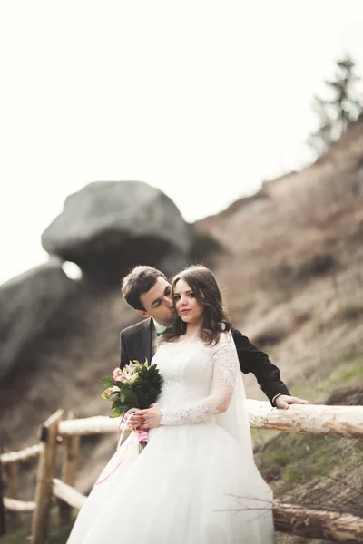 Felice coppia di nozze baciare e abbracciare vicino a una scogliera alta — Foto Stock