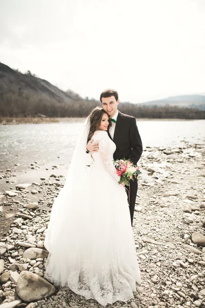 Ζευγάρι ευτυχισμένος γάμος, νύφη και ο γαμπρός που παρουσιάζουν τακτοποιημένο ποταμού με φόντο τα βουνά — Φωτογραφία Αρχείου