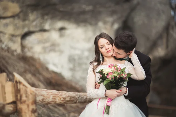 Šťastný Svatební pár líbání a objímání poblíž vysokého útesu — Stock fotografie
