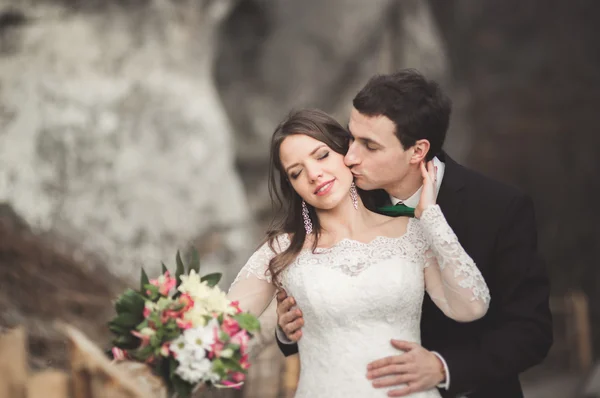 Couple de mariage heureux embrasser et étreindre près d'une haute falaise — Photo