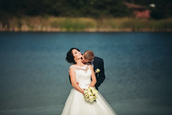 Amore e passione - bacio di coppia nuziale giovane sposata vicino a lago — Foto Stock