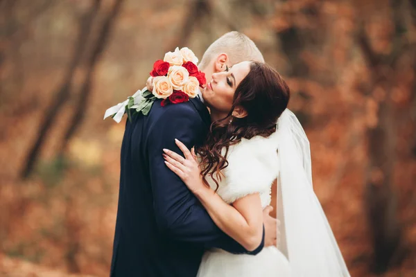 Glückliches Hochzeitspaar, Braut und Bräutigam posieren im Herbst im Park — Stockfoto