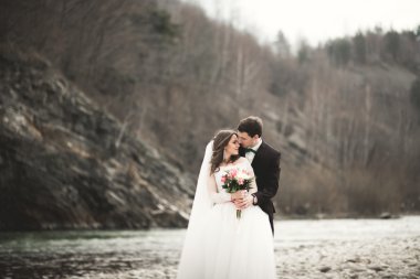 Mutlu evlilik çift, gelin ve damat zemin Dağları nın karşı temiz nehir poz