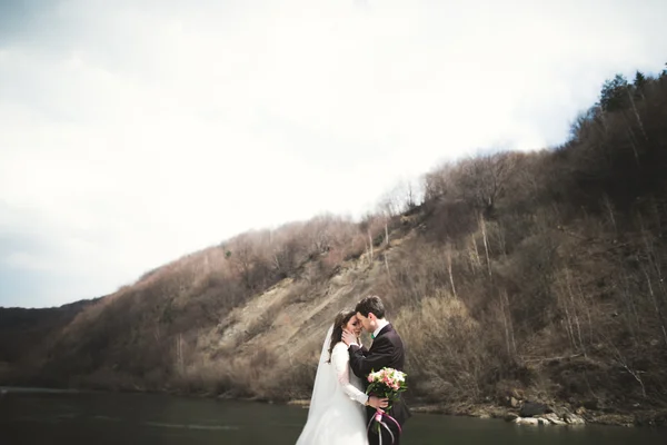 幸せな結婚式のカップル山の背景幕に対してきちんとした川をポーズ新郎新婦 — ストック写真