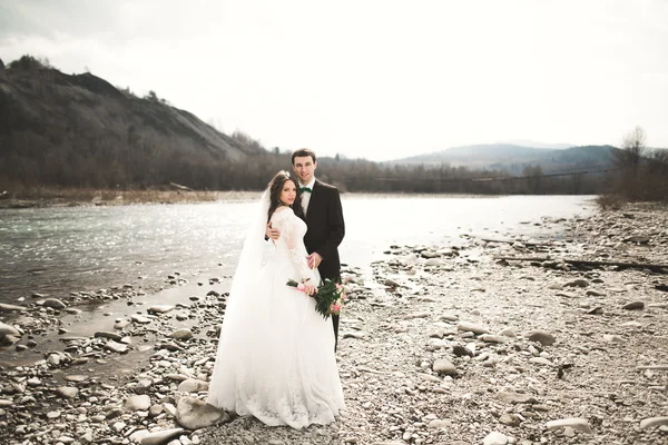 Bellissimo matrimonio coppia baciare e abbracciare vicino al fiume con pietre — Foto Stock