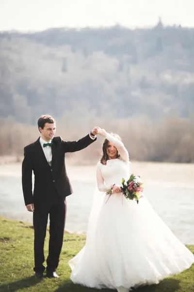 Pasangan pengantin yang cantik, pengantin wanita, berpose dan berjalan di lapangan dengan latar belakang pegunungan tinggi — Stok Foto