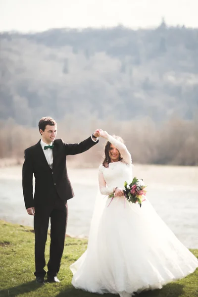 Hermosa pareja de boda, novia, novio posando y caminando en el campo sobre el fondo de las altas montañas —  Fotos de Stock