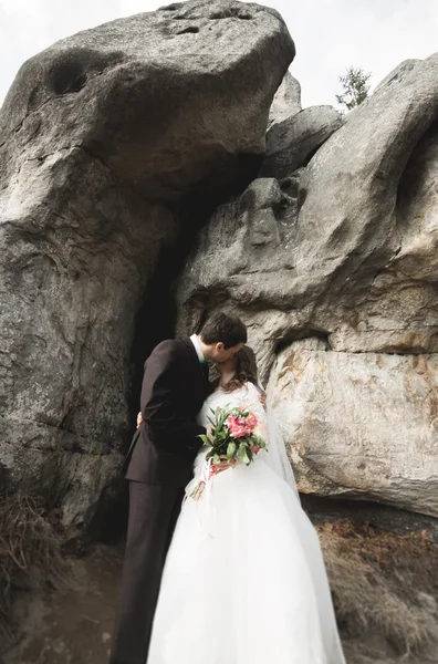 Šťastný Svatební pár líbání a objímání poblíž vysokého útesu — Stock fotografie