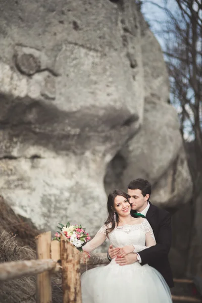 Boldog esküvői pár csók, és átölelte a következő látnivaló közelében: magas szikla — Stock Fotó