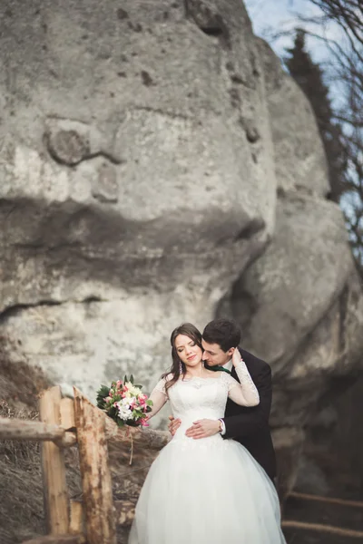 Felice coppia di nozze baciare e abbracciare vicino a una scogliera alta — Foto Stock
