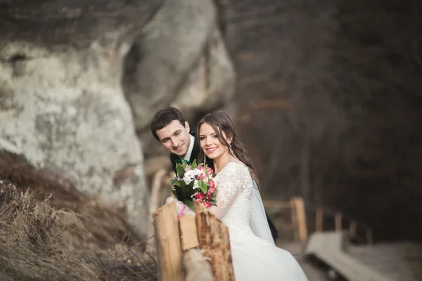 Felice coppia di nozze baciare e abbracciare vicino a una scogliera alta — Foto Stock