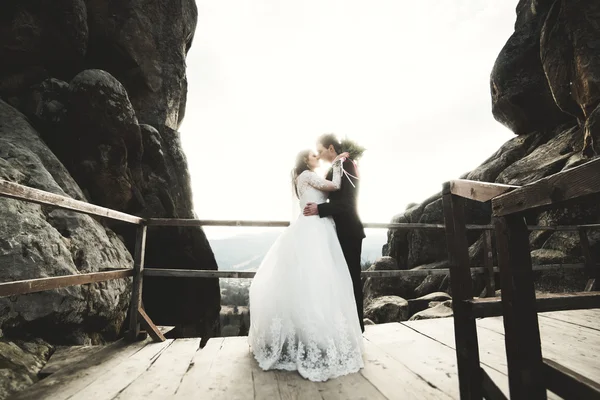 Счастливая супружеская пара, невеста и жених позируют возле скал с прекрасным видом — стоковое фото