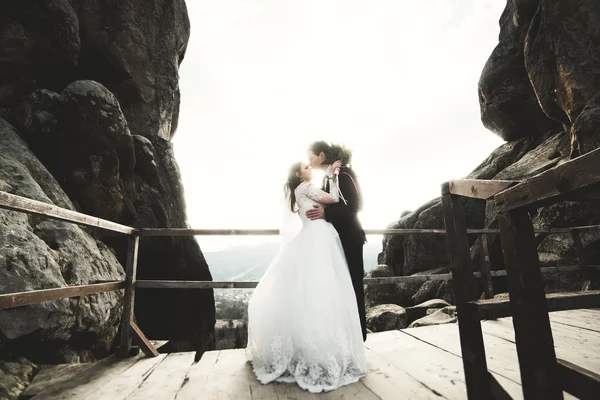 Bruiloft koppel in liefde kussen en knuffelen in de buurt van rotsen op prachtig landschap — Stockfoto