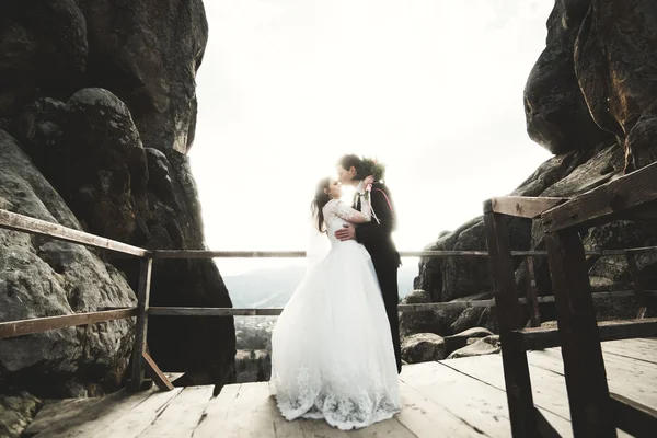 Boda pareja enamorada besándose y abrazándose cerca de rocas en hermoso paisaje —  Fotos de Stock