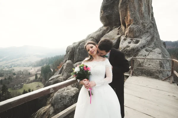 Boda pareja enamorada besándose y abrazándose cerca de rocas en hermoso paisaje —  Fotos de Stock