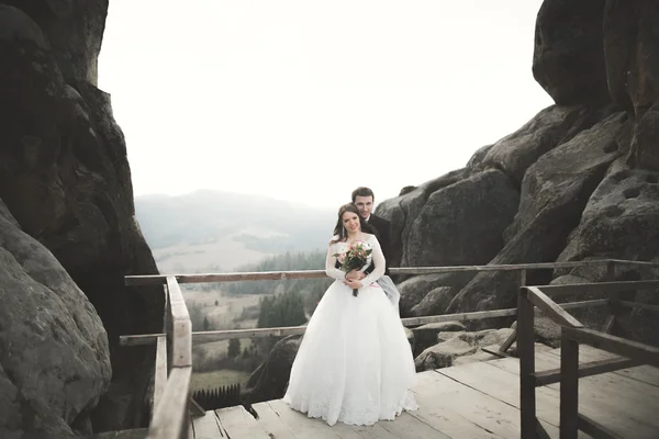 Happy wedding couple, bride and groom posing near rocks with beautiful views — Stock Photo, Image