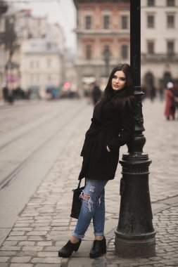 Güzel esmer genç kadın eski şehirde sokakta poz