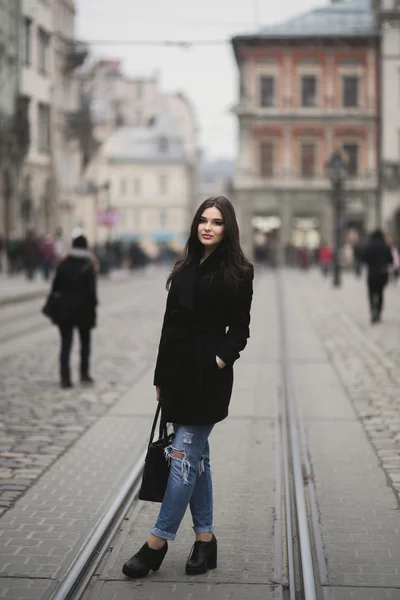 Krásná brunetka mladá žena pózuje na ulici ve starém městě — Stock fotografie
