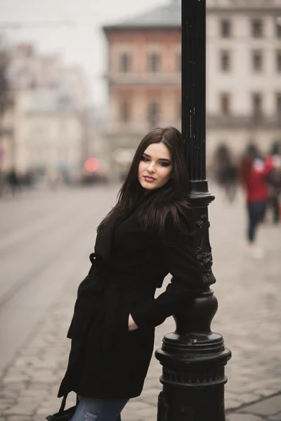 Krásná brunetka mladá žena pózuje na ulici ve starém městě — Stock fotografie