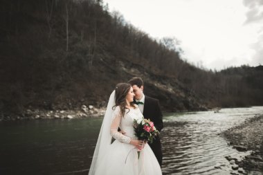 Mutlu evlilik çift, gelin ve damat zemin Dağları nın karşı temiz nehir poz