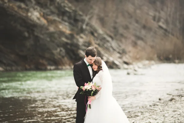 Bellissimo matrimonio coppia baciare e abbracciare vicino al fiume con pietre — Foto Stock