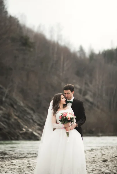 美丽婚礼情侣接吻和拥抱河边用石头 — 图库照片