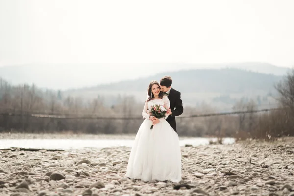 Bellissimo matrimonio coppia baciare e abbracciare vicino al fiume con pietre — Foto Stock