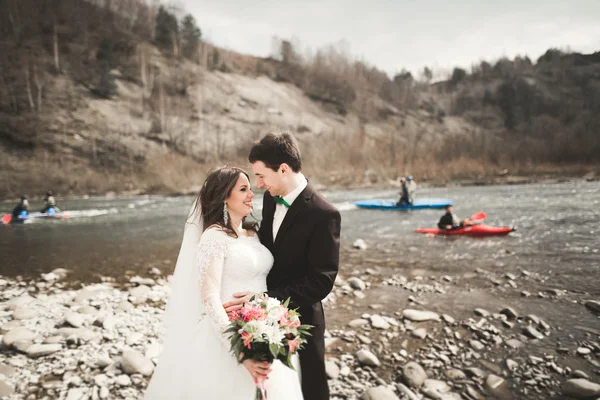 Pár boldog esküvő, a menyasszony és a vőlegény jelentő ügyes folyó a hegység — Stock Fotó