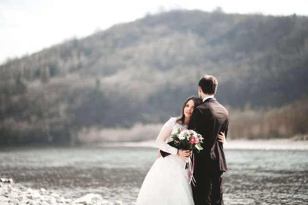 Feliz recién casados, novia y novio posando en el río con hermosas vistas —  Fotos de Stock