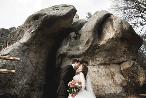 Šťastný Svatební pár líbání a objímání poblíž vysokého útesu — Stock fotografie
