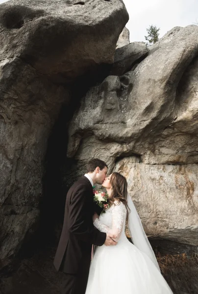 Glückliches Hochzeitspaar küsst und umarmt sich in der Nähe einer hohen Klippe — Stockfoto